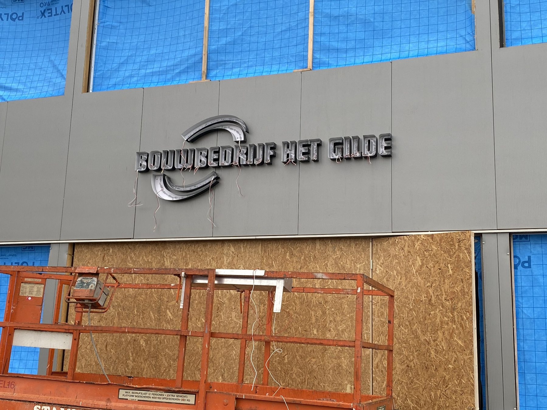 Het logo van het Gilde wordt op de gevel gemonteerd